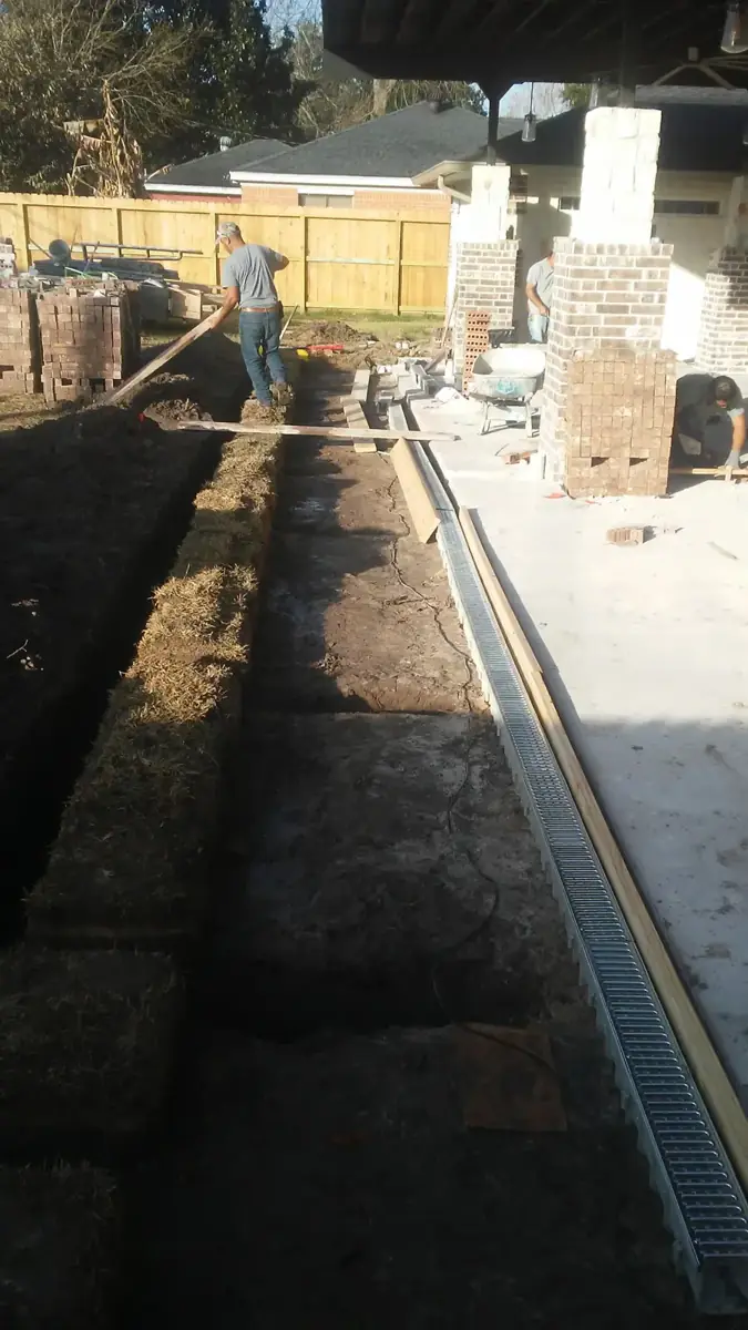 Excavated trench running alongside a channel drain at the edge of a new concrete slab