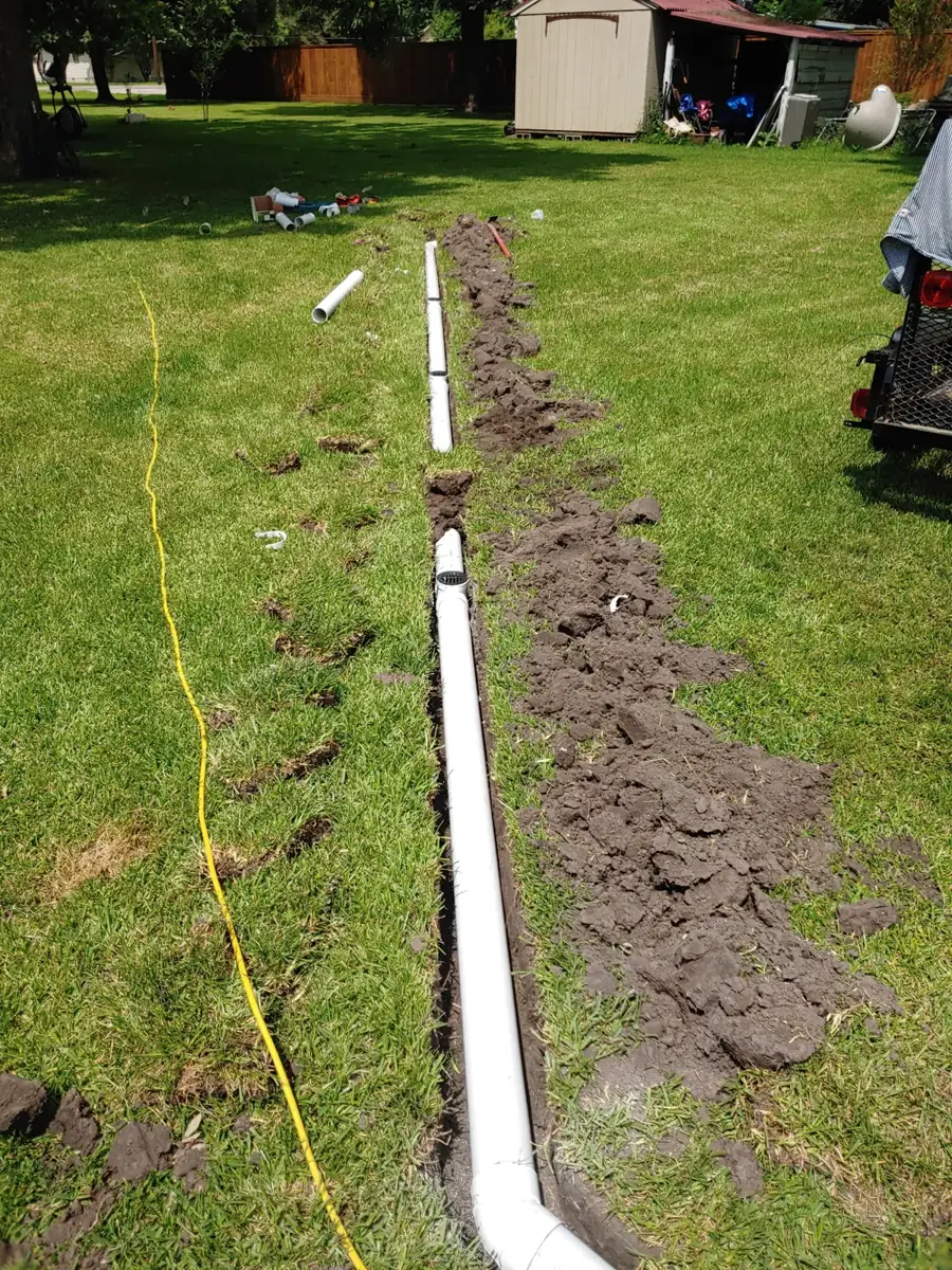 Long white drain pipe trench running across a backyard lawn